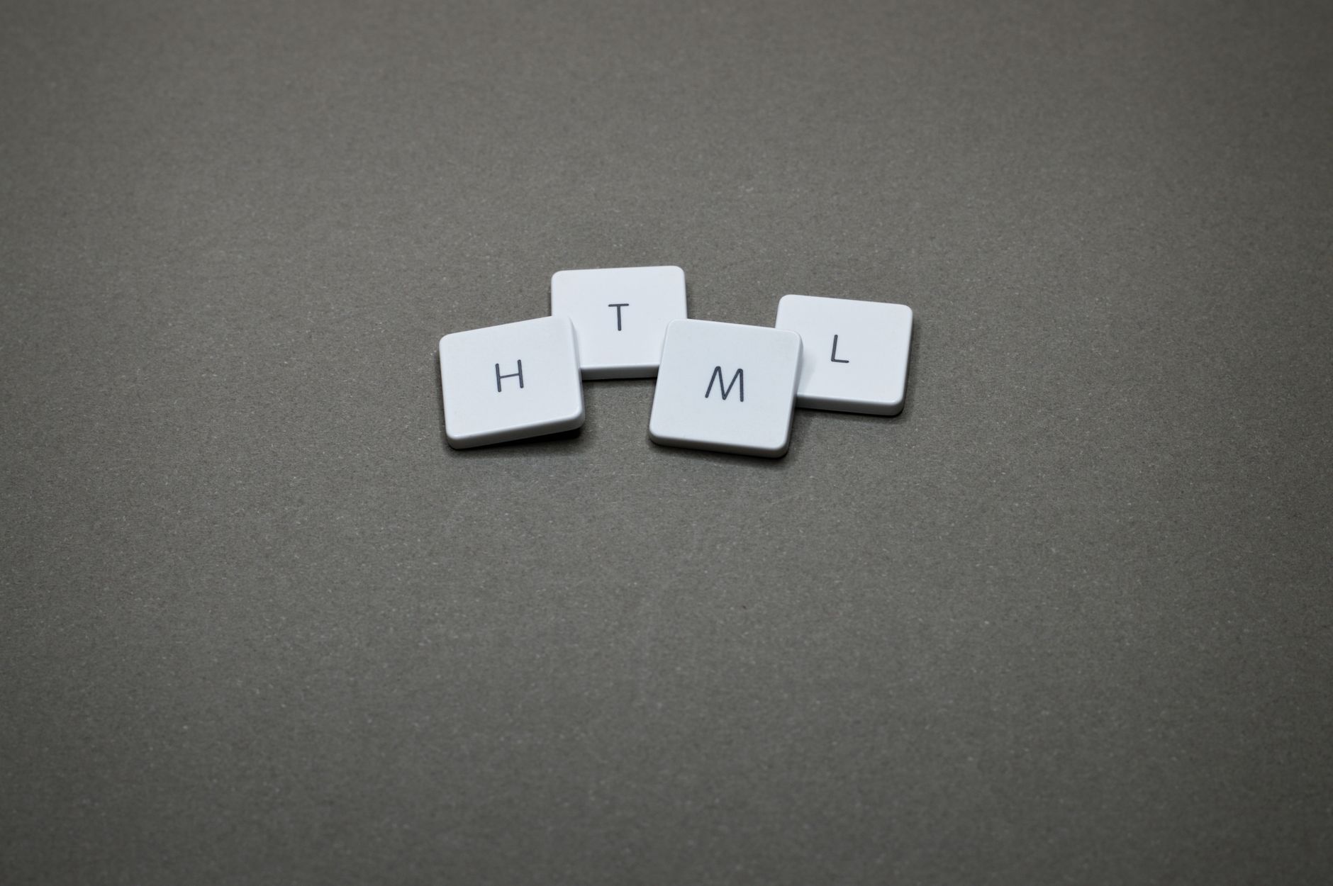 White keyboard keycaps arranged to spell HTML on a gray background