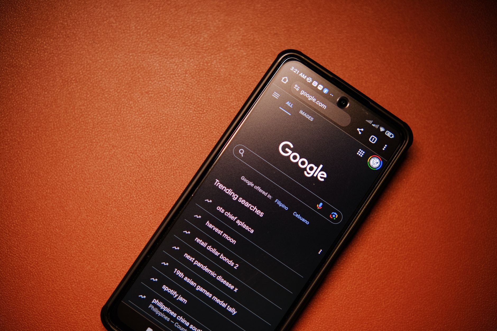 Smartphone affichant la page d'accueil Google sur un fond orange